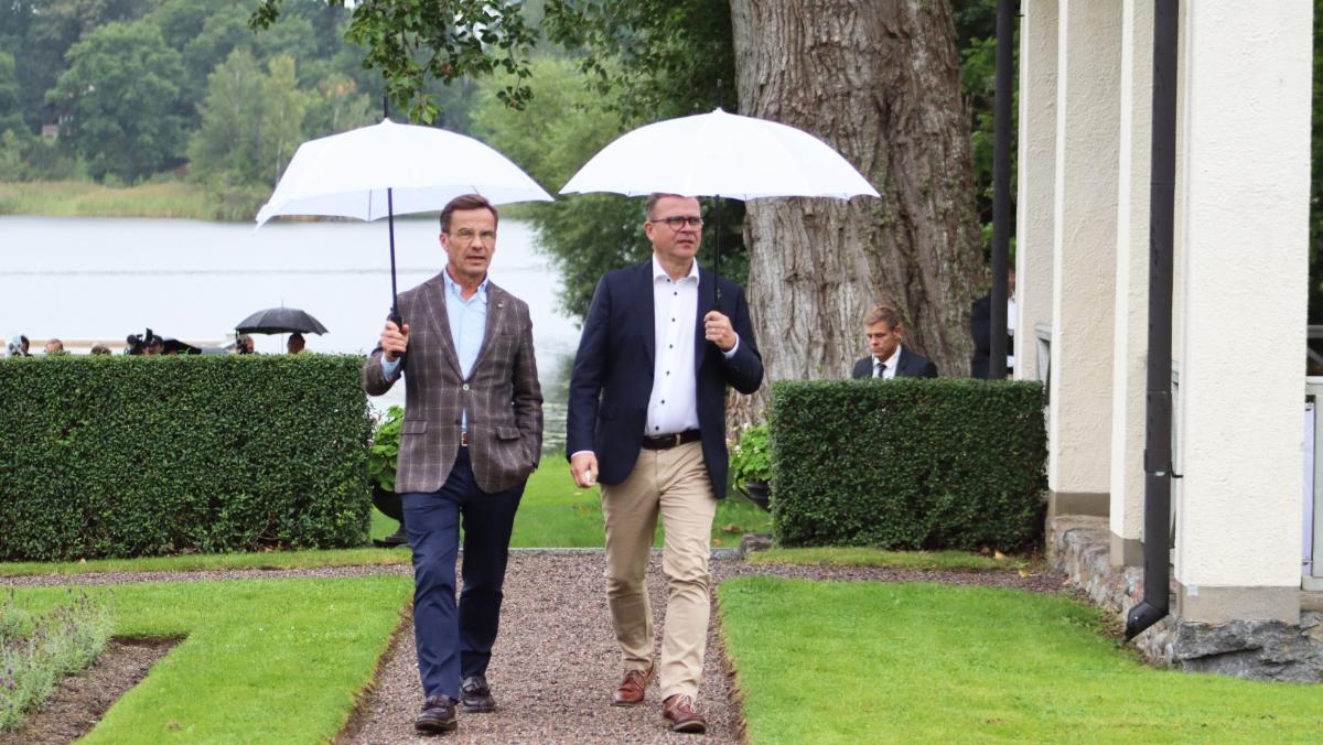 Prime Minister Petteri Orpo and Sweden's Prime Minister Ulf Kristersson walk under umbrellas.