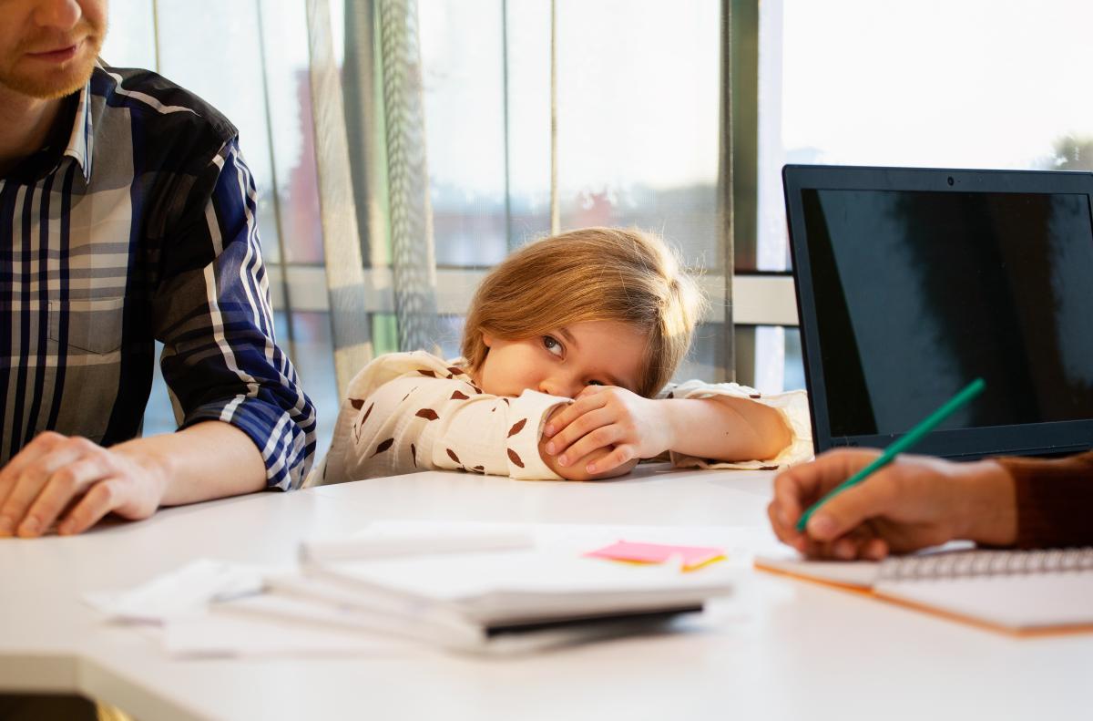 Pöydän ääressä kaksi aikuista ja yksi lapsi.