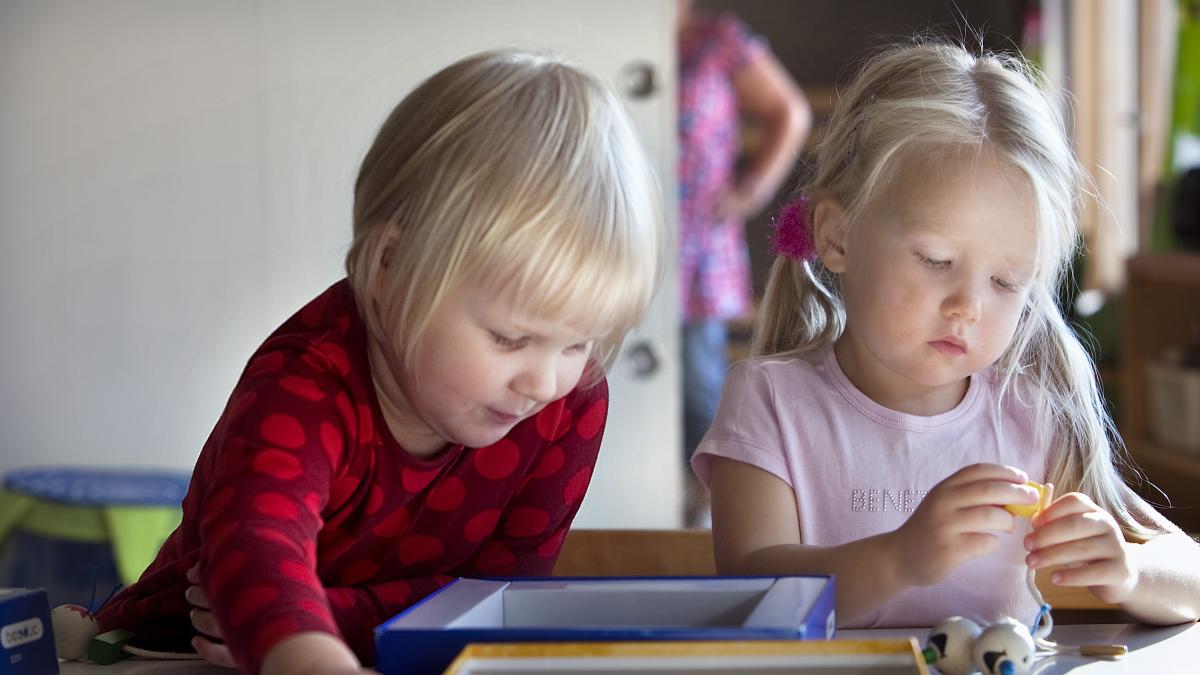 Kaksi lasta askartelee pöydän ääressä