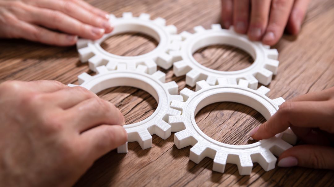 Neljä hammasratasta pöydällä käsien ohjaamana.