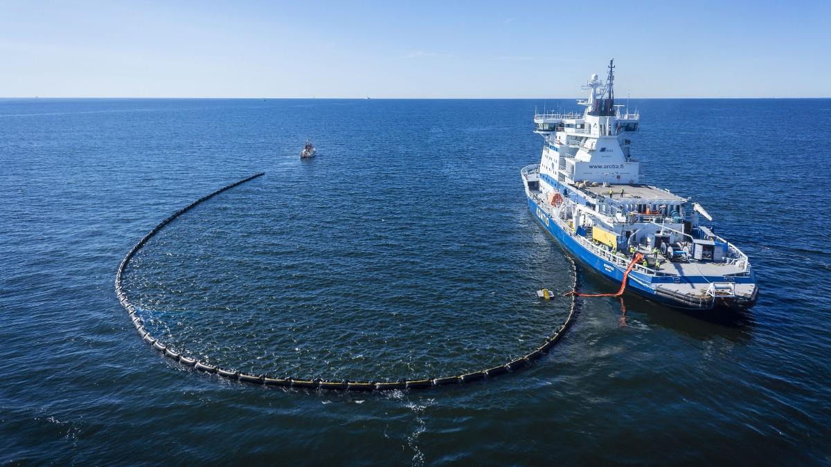 Arctian Kontio-laiva harjoittelemassa öljyntorjuntaa merellä, taustalla sininen taivas.