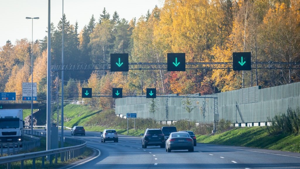 Autot ajavat monikaistaista tietä, jonka yläpuolella on digitaalisia kaistamerkintöjä.
