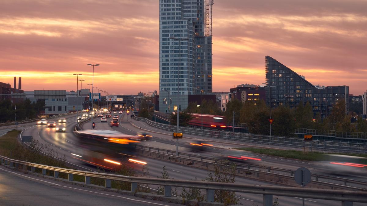 Liikkeessä olevia autoja Helsingin Kalasatamassa auringon laskiessa.