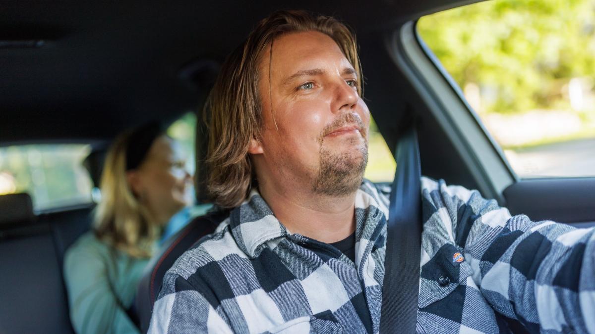 Mies ajaa autoa nainen takapenkillä.