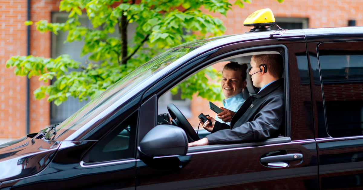 En man sitter i en taxi och betalar en resa med en telefon. (Fto: Keksi, Mika Pakarinen)