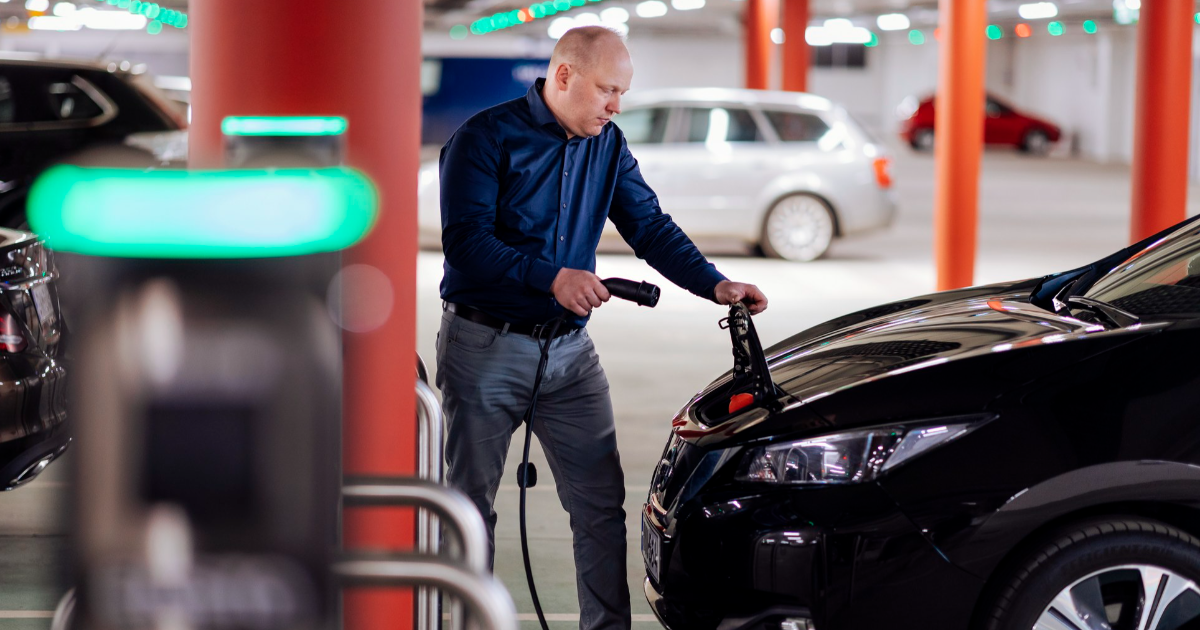 En bilist laddar en elbil i en parkeringshall. (Bild: Mika Pakarinen, Keksi / Kommunikationsministeriet)