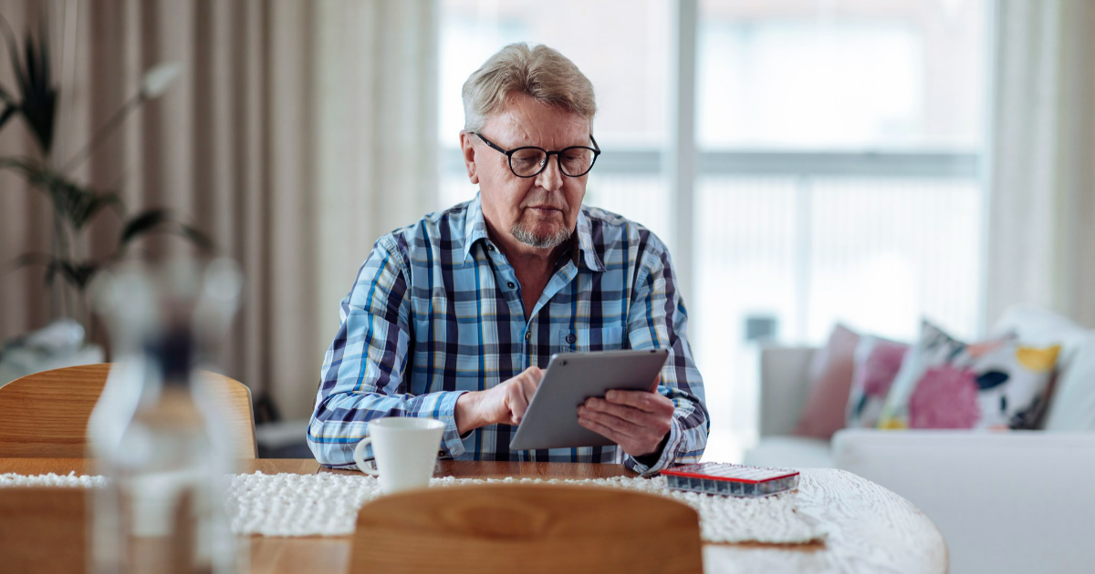 Mies selailee tablettia keittiön pöydällä. (Kuva: Mika Pakarinen, Keksi / LVM)