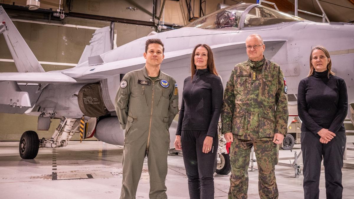 Ryhmäkuva, jonka taustalla näkyy Lapin lennoston kalustoa