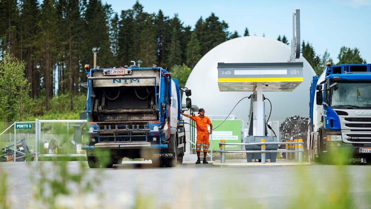 Biokaasukäyttöinen jäteauto tankattavana, ihminen nojailee autoon