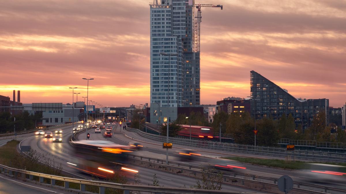 Liikkeessä olevia autoja Helsingin Kalasatamassa auringon laskiessa.