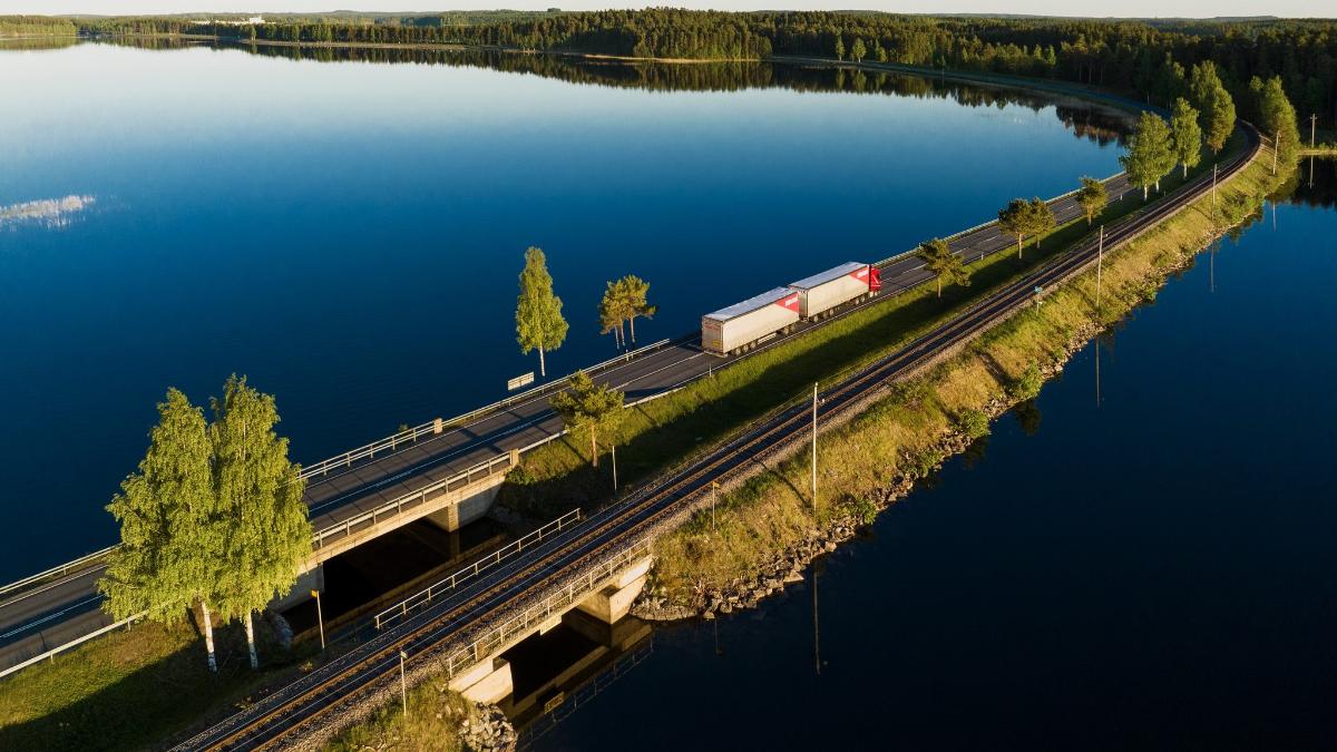 Rekka ajaa tiellä, jonka molemmin puolin on järvi.