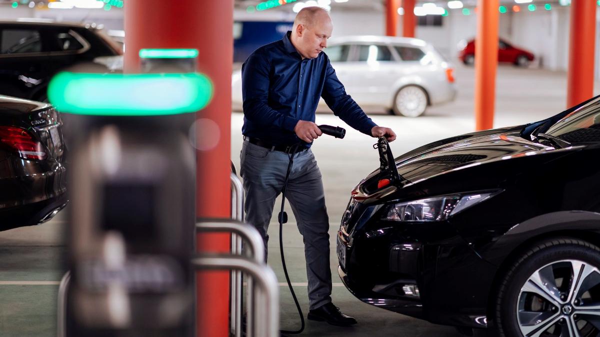 Ihminen laittamassa sähköautoa lataukseen parkkihallissa.