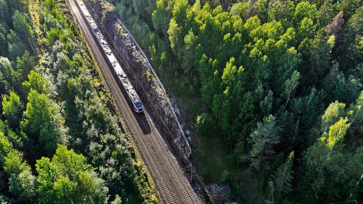 Ilmakuva, jossa juna kulkee raiteilla metsän keskellä