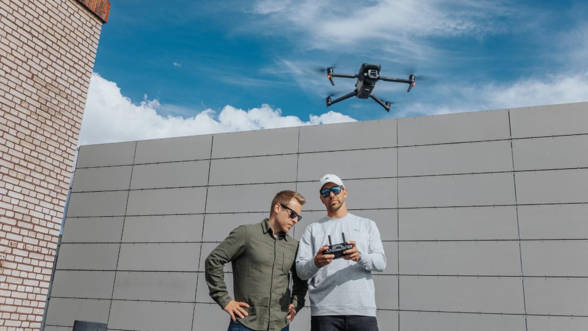 Kaksi ihmistä ohjaamassa dronea