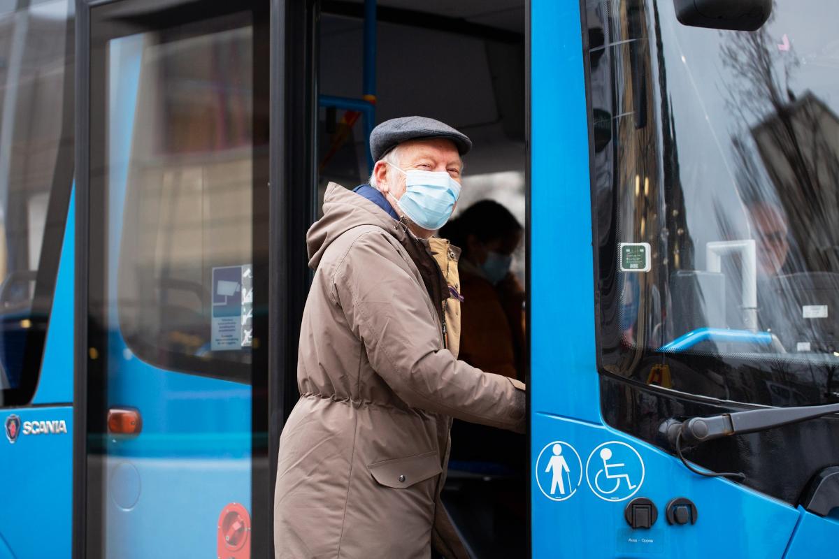 Seniori nousee bussiin maski päällä