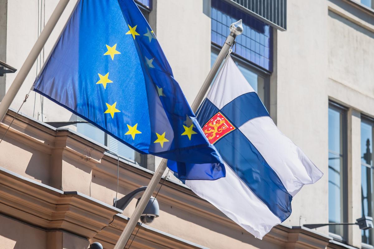 Kuvassa Suomen lippu ja EU-lippu rakennuksen lipputangoissa