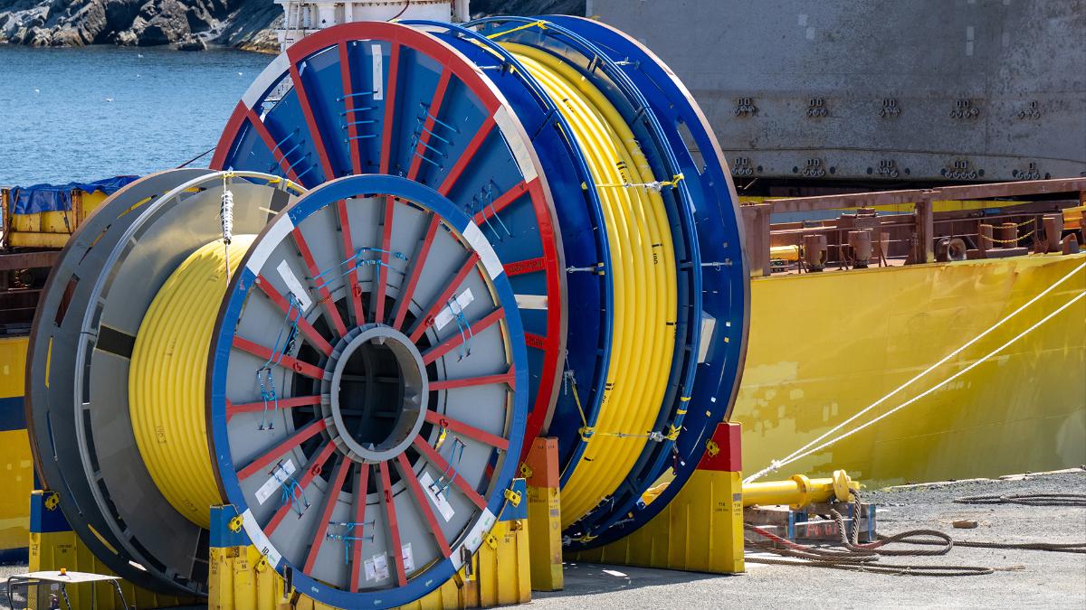 Kaksi värikästä merikaapelirullaa satamassa, taustalla näkyy merta.