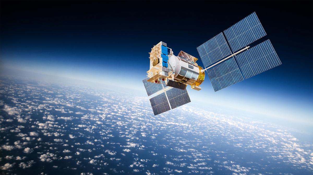 Satelliitti avaruudessa, taustalla pilvien ympäröimä maapallo