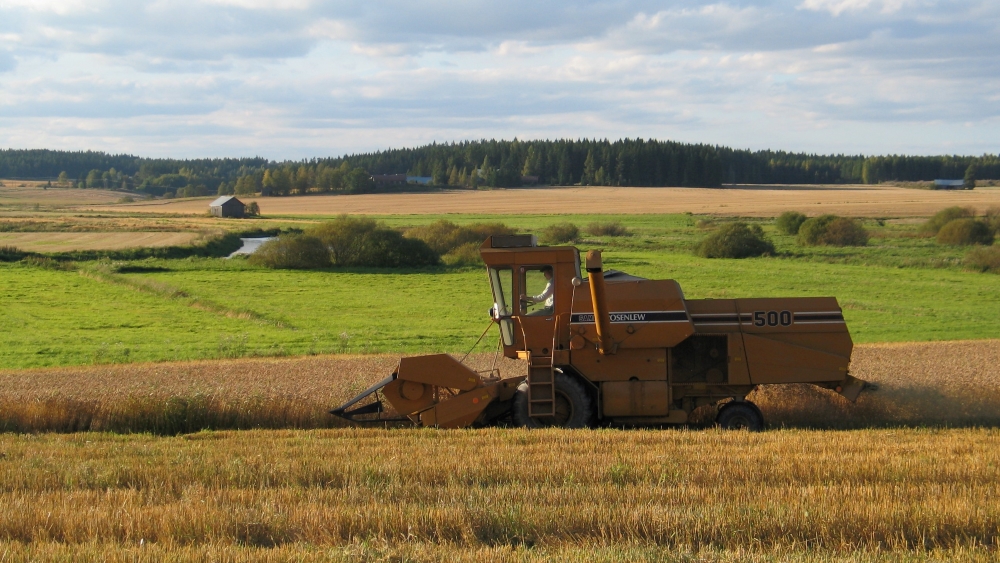 Kuvassa peltomaisema ja puimuri