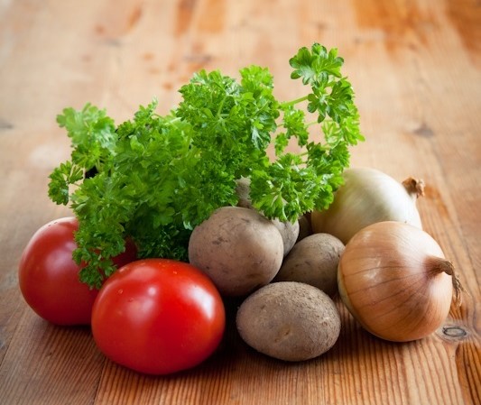 perunoita, salaattia ja tomaatteja pöydällä. Kuvituskuva.