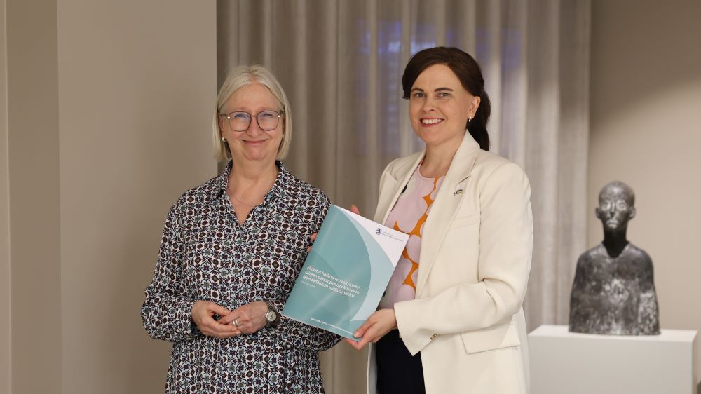 Työryhmän puheenjohtaja, johtaja Minna Karvonen luovutti työryhmän esityksen tiede- ja kulttuuriministeri Mari-Leena Talvitielle. Käsissä työryhmämuistio.