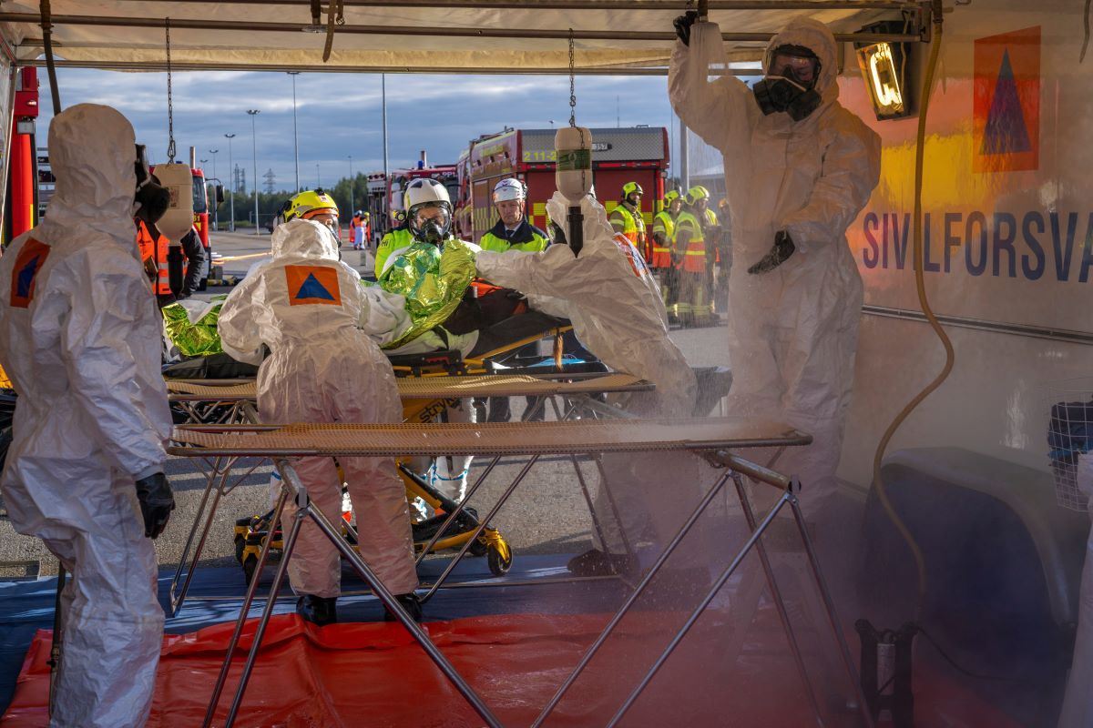 Kuvassa simulaatiossa norjalaisen puhdistuslinjaston ammattilaiset valmistelevat myrkylliselle kemikaalille altistuneen potilaan kuljetusta Oulun yliopistolliseen sairaalaan. Kuva: Sisäministeriö
