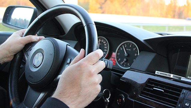 Autoilijan kädet ratissa.