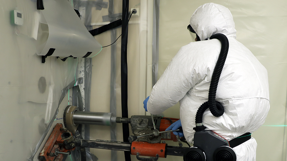 Työmies valkoisissa suojavaatteissa FIR 1 -tutkimusreaktorin purkutyömaalla