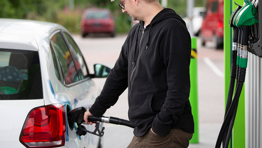 Mies tankkaa bensiiniä huoltoasemalla autonsa tankkiin