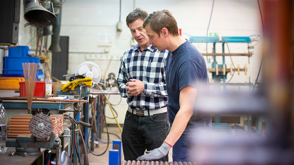 Esimies ja alainen keskustelevat metallialan yrityksessä