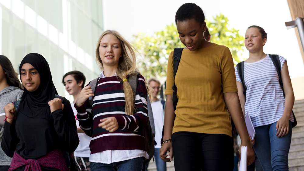 Nuoria kävelemässä reppu selässä portaita alaspäin