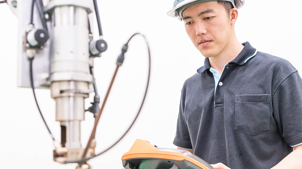 Photo: En international man arbetar som en ingenier vid vita hjelm i fabrik.