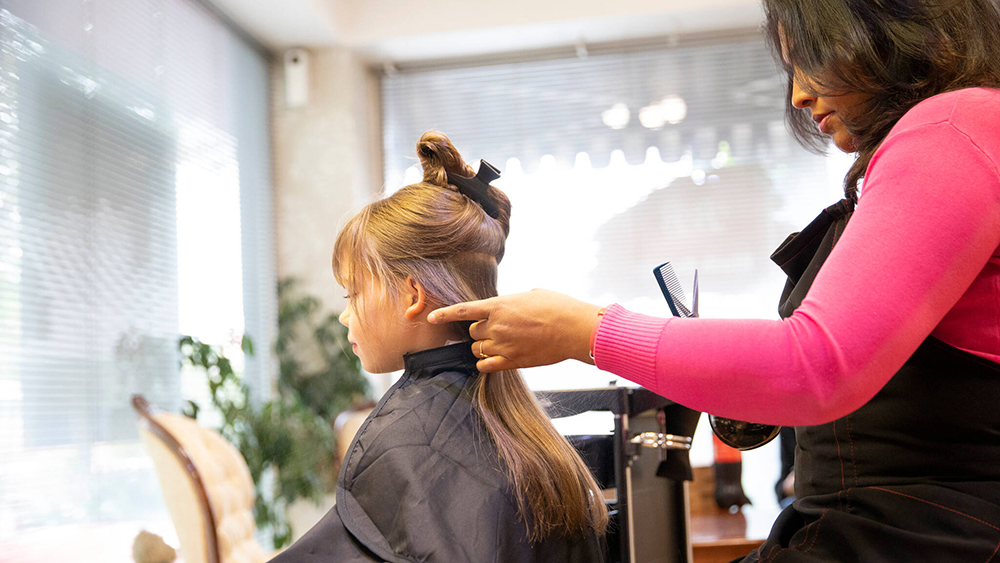 Kuvituskuva, jossa kampaajayrittäjä työskentelee asiakkaan hiuksia leikkaamassa.