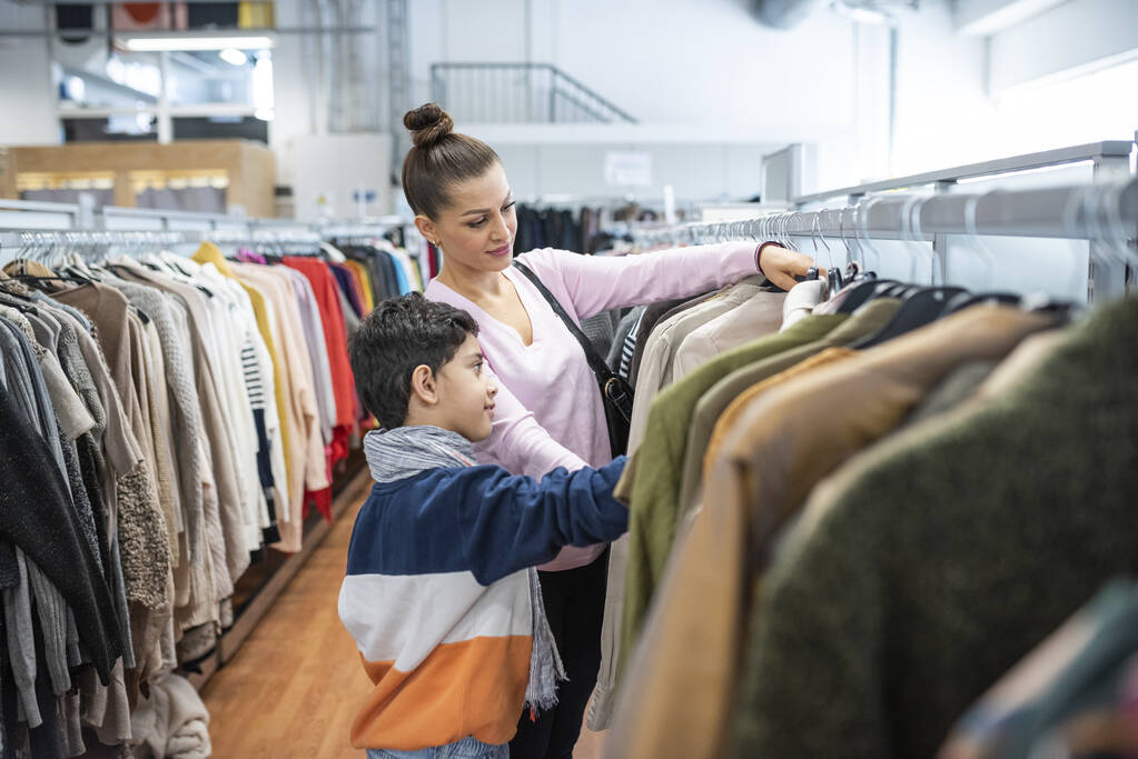 Nainen ja poika katselevat vaatteita kierrätyskeskuksessa.