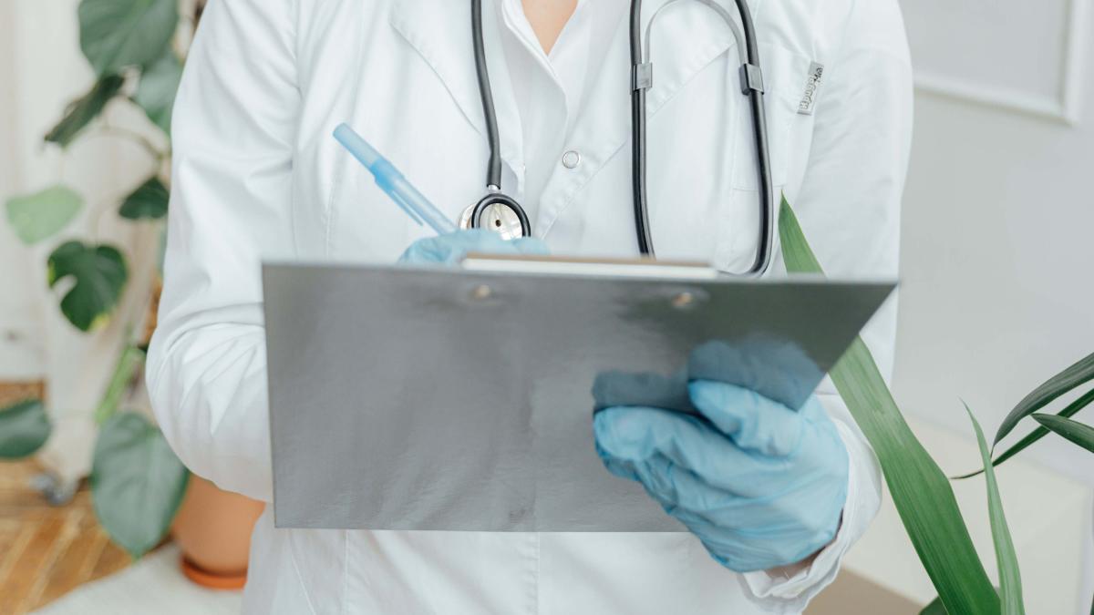 Lääkärillä kädessään kirjoitusalusta ja kynä.