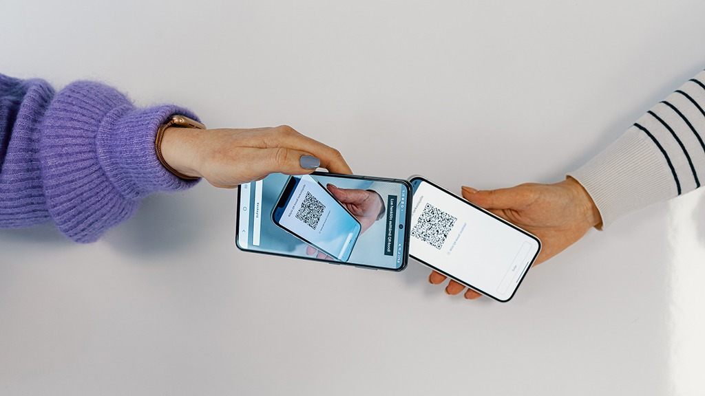 En person använder sin telefon för att läsa en QR-kod från en annan telefons skärm