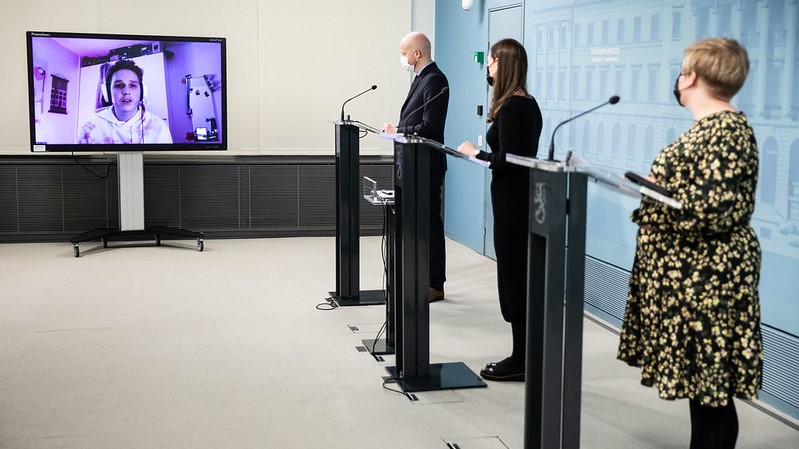 Opetusministeri Jussi Saramo, pääministeri Sanna Marin ja tiede- ja kulttuuriministeri Annika Saarikko katsovat tv-monitoria ja kuuntelevat opiskelijan kysymystä.