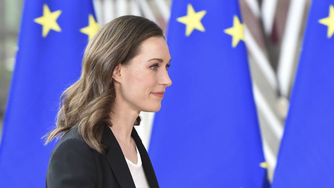 Prime Minister Marin walking, EU flags on the back round