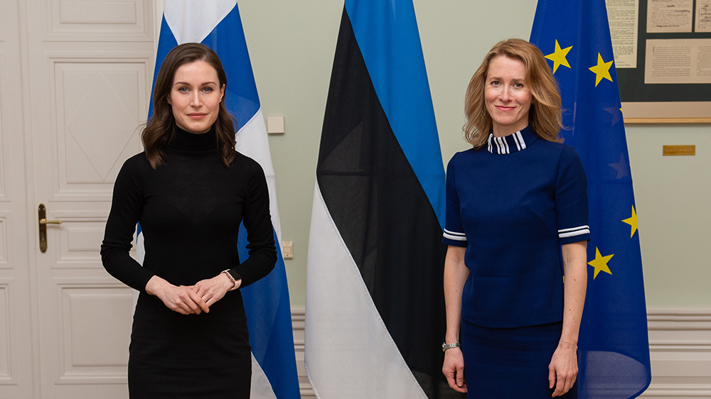 Prime Minister Marin and Prime Minister Kallas standing on the front of Finnish, Estonian and EU flags
