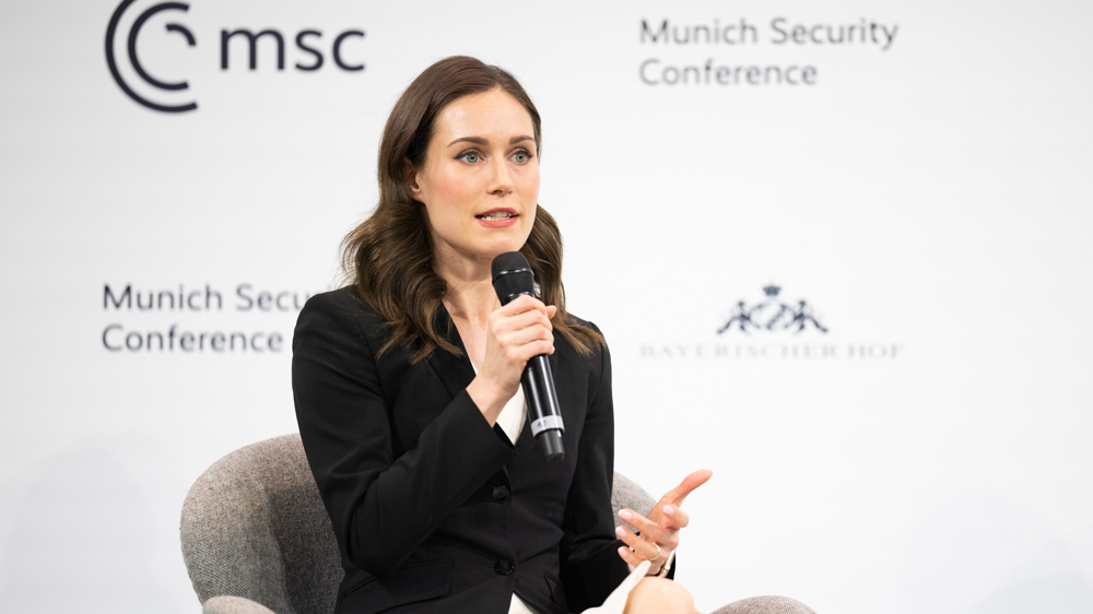 Pääministeri istuu ja Marin puhuu paneelikeskustelussa konferenssissa