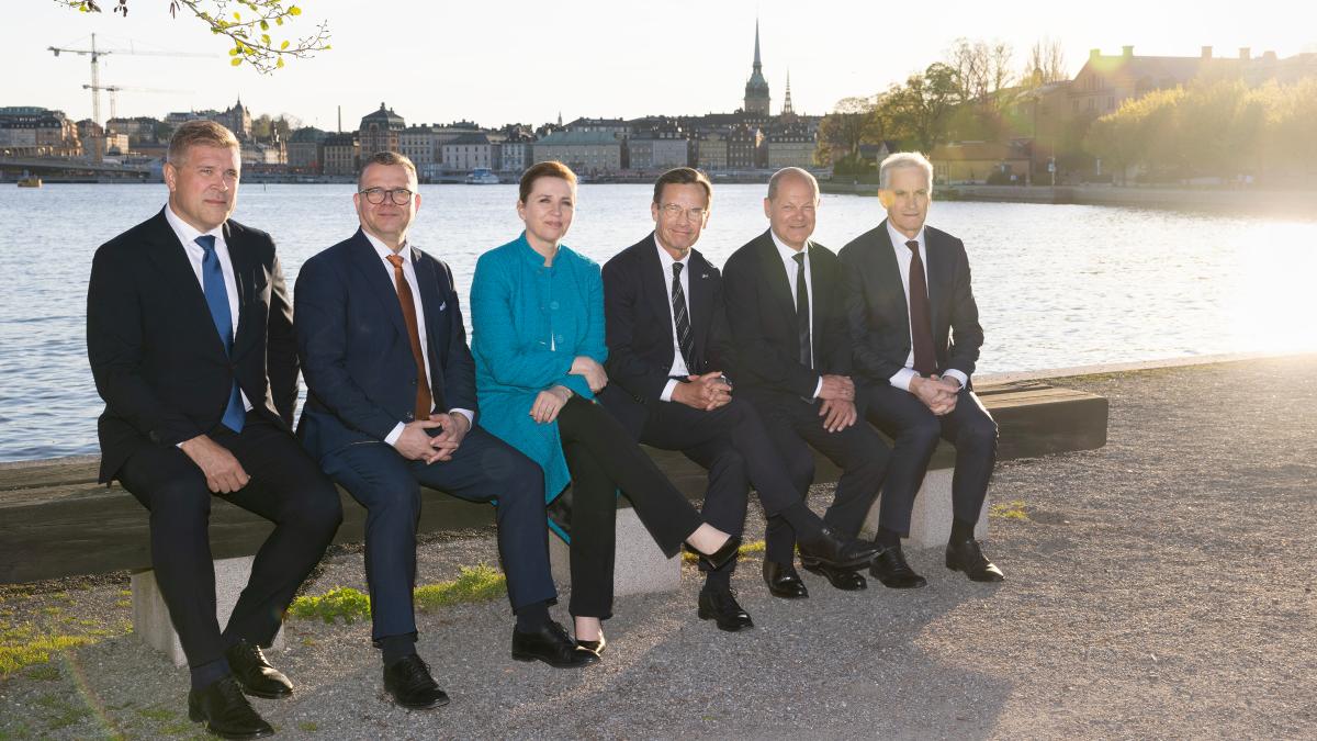 Pohjoismaiden pääministerit ja Saksan liittokansleri istuvat penkillä ilta-auringossa. Takana Tukholman kaupunkia.