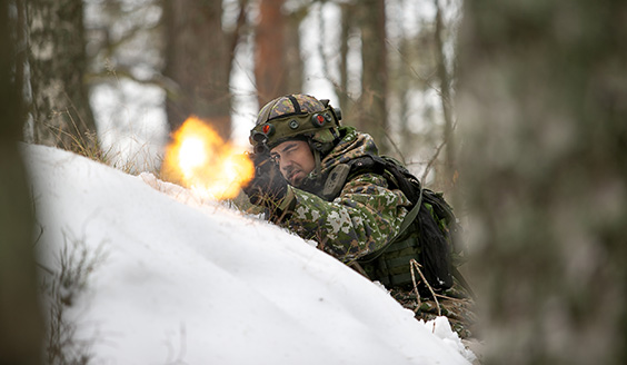Sotilas ampumassa rynnäkkökiväärillä talvisessa metsämaastossa.