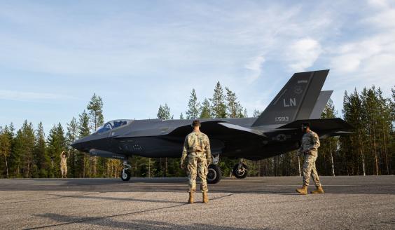 Yhdysvaltalainen F-35A-hävittäjä maantieosuudella, taustallaan suomalaista syksyistä sekametsää. Kolme yhdysvaltalaissotilasta katsovat hävittäjää, ja yksi heistä ohjeistaa konetta rullaamaan haluttuun paikkaan.