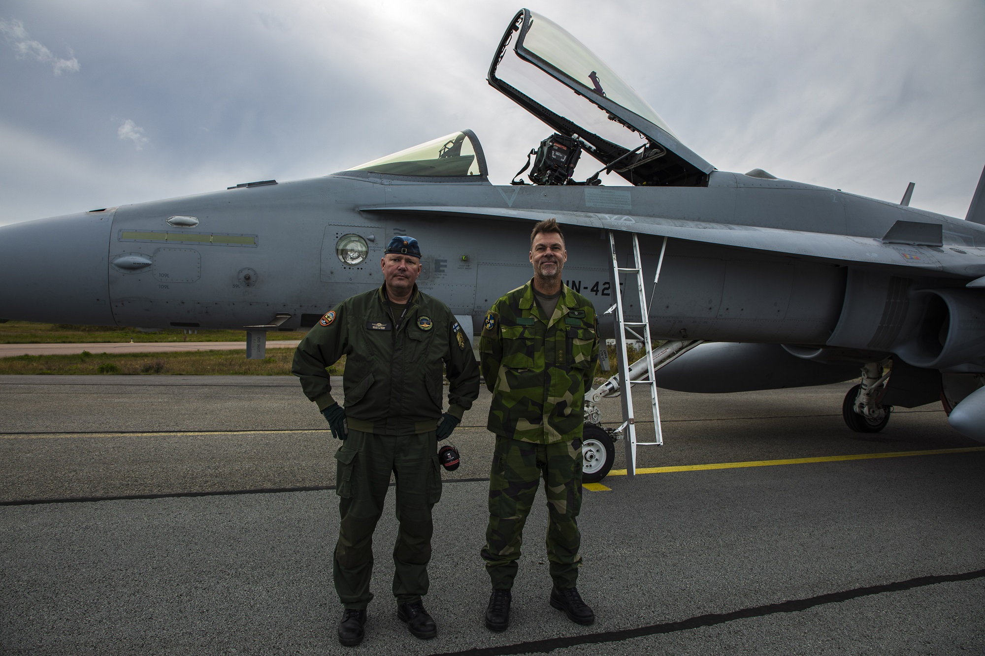 Chief Master Sergeant Veli-Matti Terämä and Swedish Air Force Master Sergeant Peter in front of a Finnish F/A-18 Hornet fighter jet.