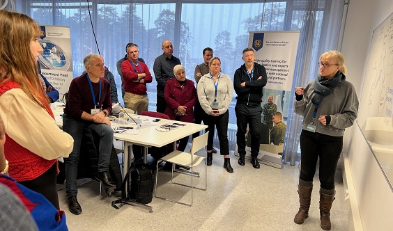 Course participants standing in fornt of white board listening an expert