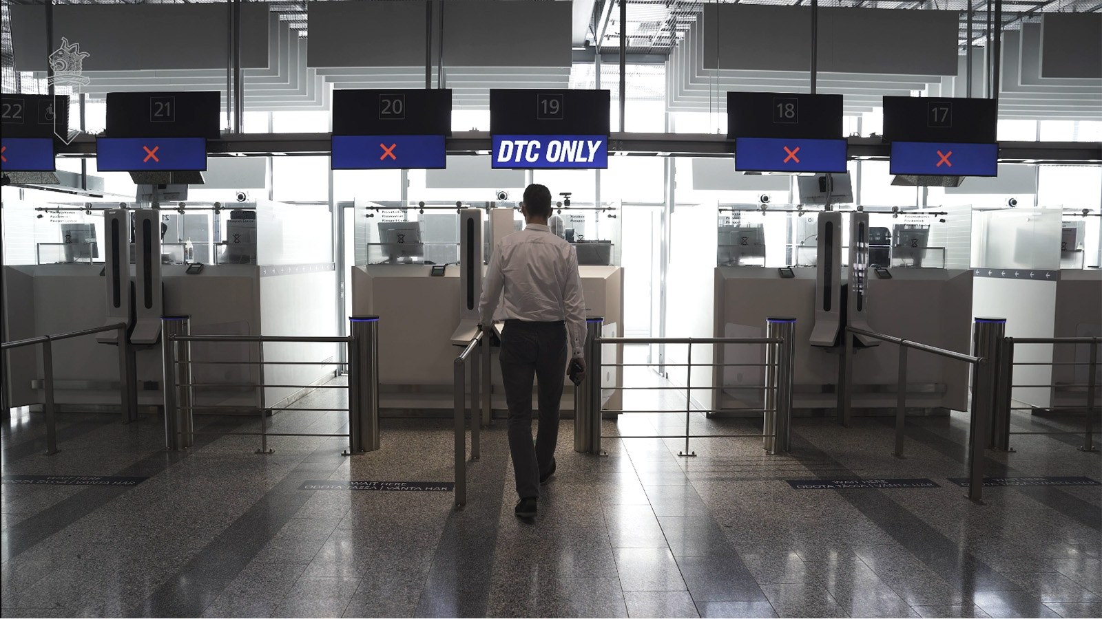 A man walks towards a counter marked with a DTC sign in an airport lobby