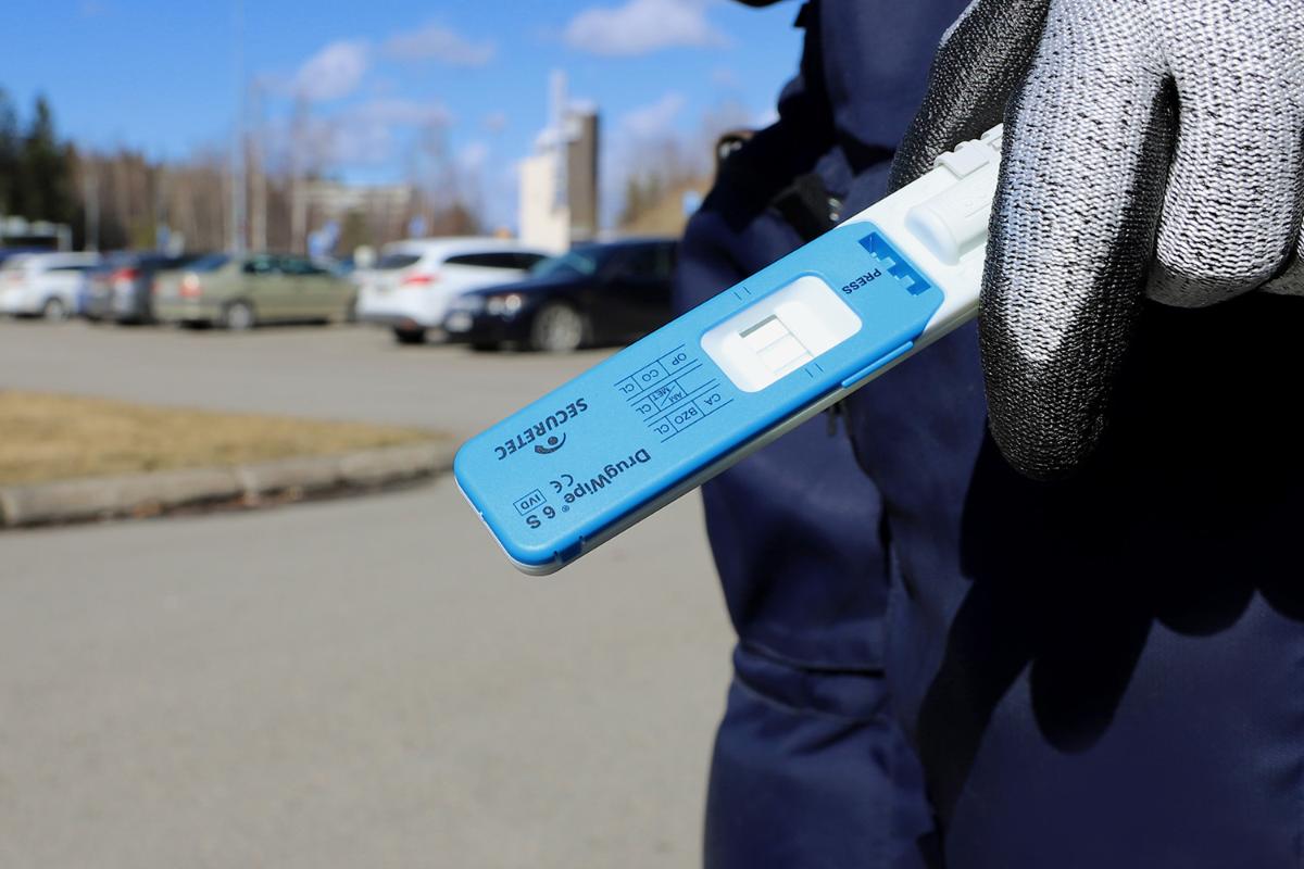 A hand with a drug test. Cars in the background.