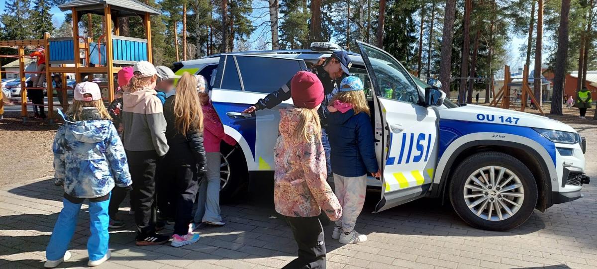 Poliisi esittelee poliisiautoa lapsille.