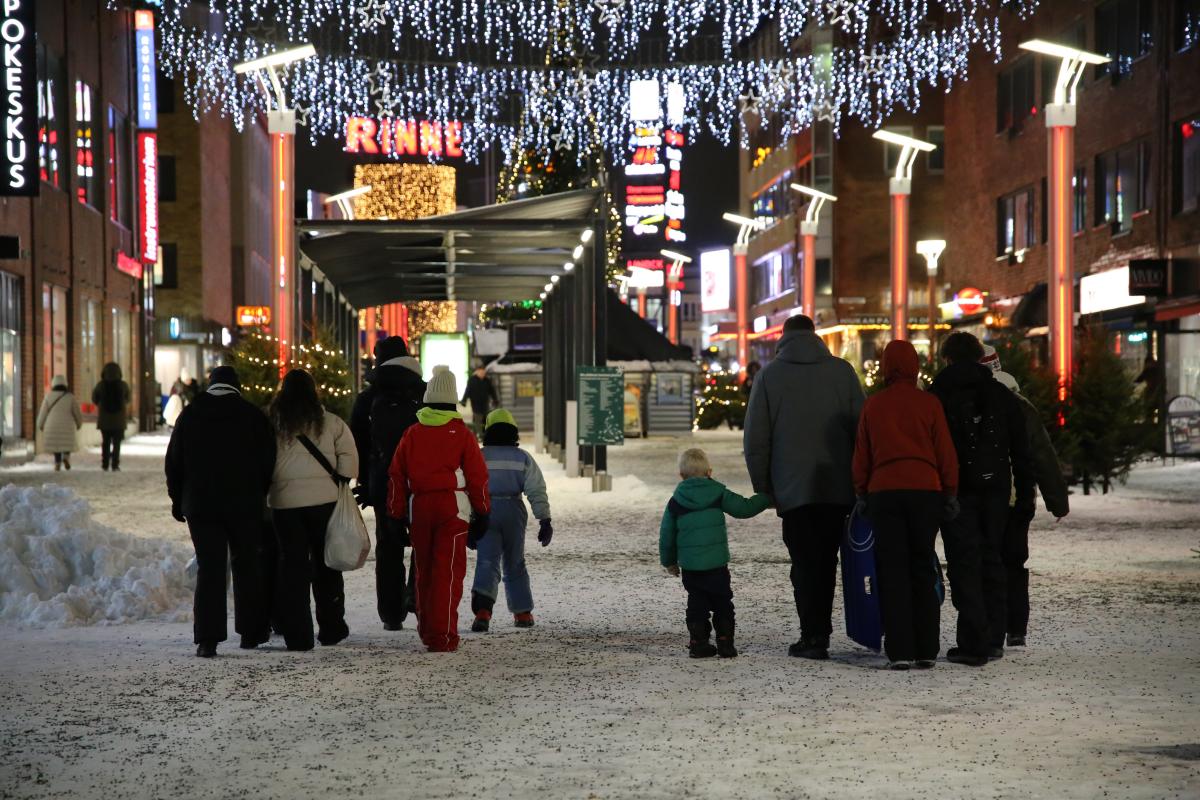 Two families are walking on a Christmas street.