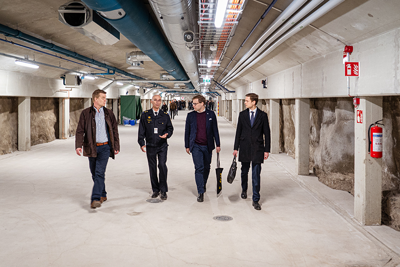 Neljä miestä kävelee väestönsuojassa.